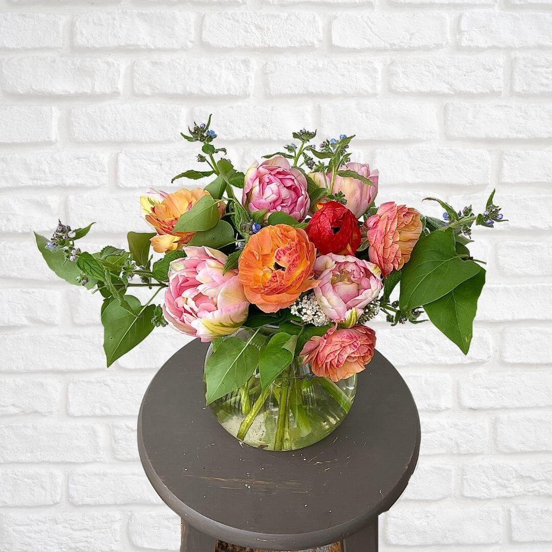Beautiful seasonal flower arrangement of orange, white and yellow colored blooms. Hand arranged and presented in a glass vase with our signature twine finish.